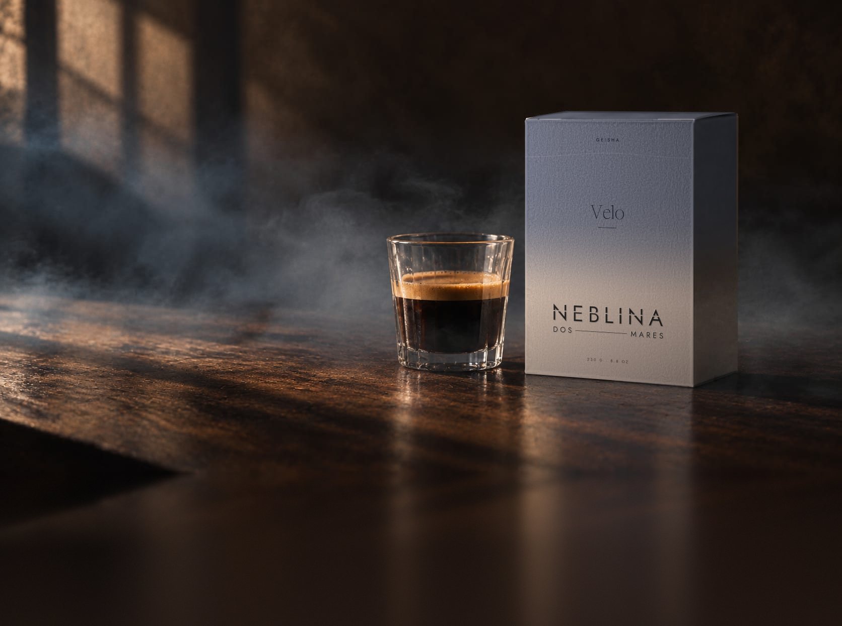Caja Neblina con banda azul claro junto a un vaso de espresso, sobre madera oscura y con neblina baja cruzando la escena